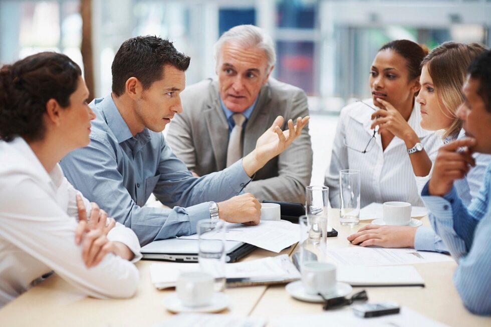 Equipo de profesionales debatiendo en una reunión de trabajo alrededor de la mesa