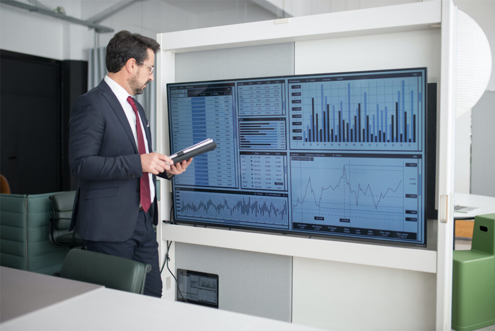 Ejecutivo revisando indicadores y gráficos financieros en una pantalla de monitoreo