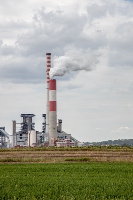 Chimenea de una planta termoeléctrica junto a campos de cultivo